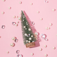 Creative layout with Christmas tree, white pearls and diamonds cocktail glasses on  pastel pink background. Retro fashion aesthetic party concept. Minimal New Year or Christmas celebration idea.