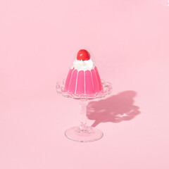 Pink jello on dish with cherry on top on pastel pink background. 70s or 80s retro style aesthetic dessert idea. Minimal food concept. - obrazy, fototapety, plakaty