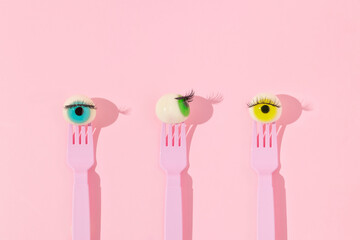 Creative pattern with eyeball figurines on pink forks on pastel pink background. Halloween...