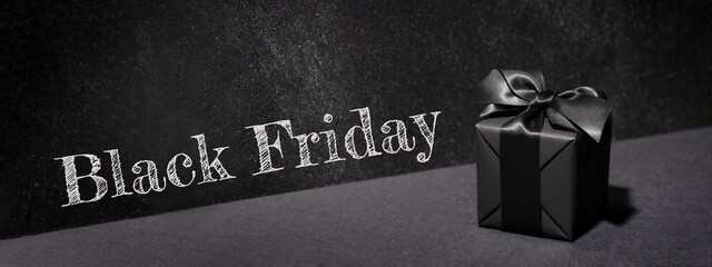 Black Friday banner with black gift box on black background.
