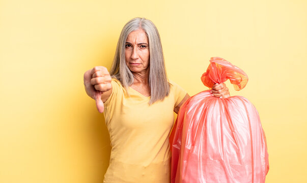 middle age pretty woman feeling cross,showing thumbs down. plastic garbaje bag