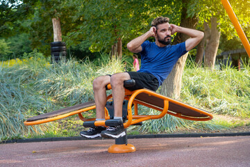 Man shakes the press on the bench at the city park open air gym