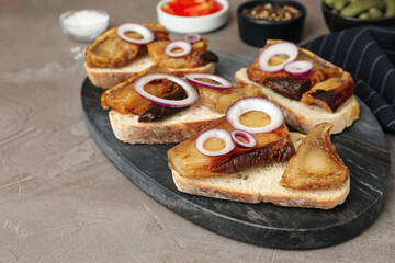 Obraz na płótnie Canvas Tasty fried pork lard with bread slices and onion on grey table