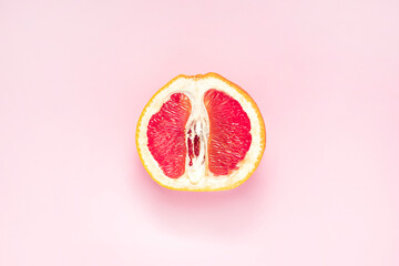 Half of fresh grapefruit on pink background. Symbol of vagina. Gynecology, female intimate health, menstruation concept. - obrazy, fototapety, plakaty