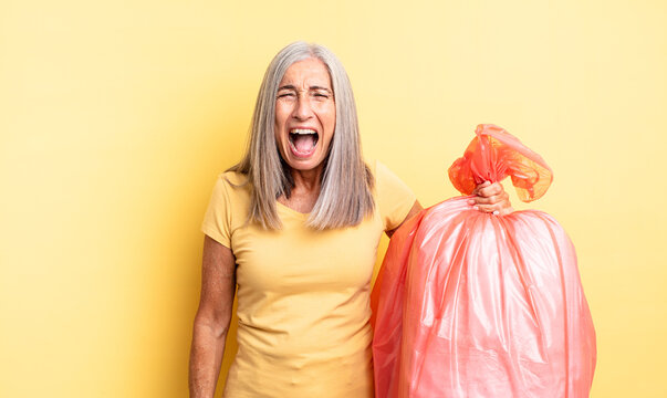 middle age pretty woman shouting aggressively, looking very angry. plastic garbaje bag