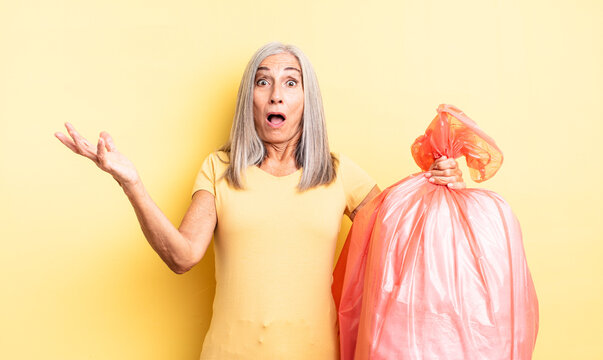 middle age pretty woman amazed, shocked and astonished with an unbelievable surprise. plastic garbaje bag