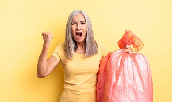 middle age pretty woman shouting aggressively with an angry expression. plastic garbaje bag