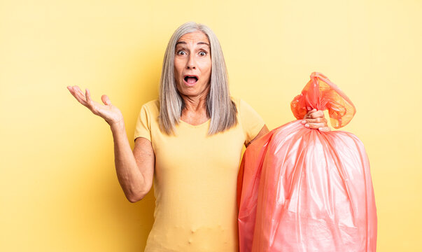 middle age pretty woman feeling extremely shocked and surprised. plastic garbaje bag