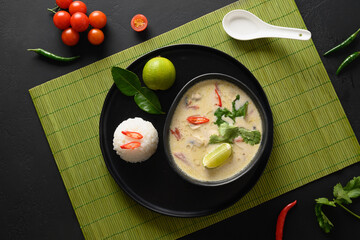 Spicy creamy Tom Kha Gai soup with chicken, cherry tomato, coconut milk, kaffir, galangal, lemongrass,mushrooms. Asian Thai food. Coconut Chicken Soup. Top view.