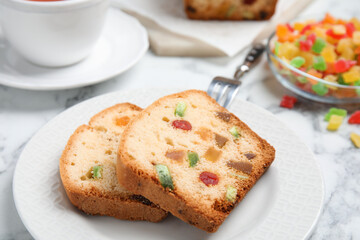 Delicious cake with candied fruits and tea on table, closeup