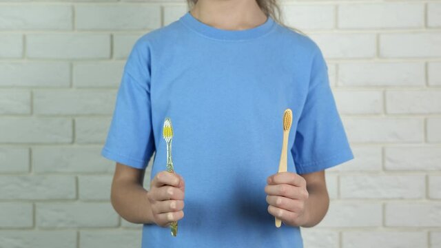 A plastic or wooden toothbrush. The girl holds a plastic toothbrush in her hands.