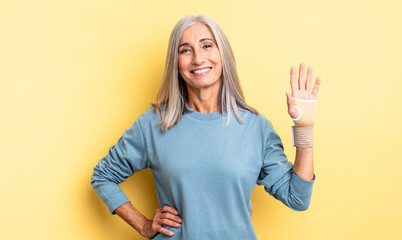 middle age pretty woman smiling happily with a hand on hip and confident. hand bandage concept