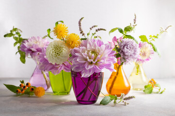 Autumn still life with bouquets of flowers in multicolored vases on table. Autumn floral decoration...