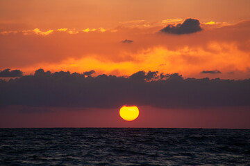 Sunset with huge sun falling on the sea at Aphrodite beach in Cyprus