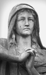 Close up ancient stone statue of woman on a tomb as a symbol of depression pain and sorrow. Black and white image.