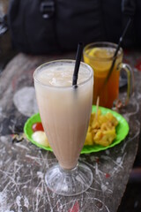 Glass of iced coffee milk on wooden table with blur background. Refreshing food. Milkshake in transparent glass on food background.