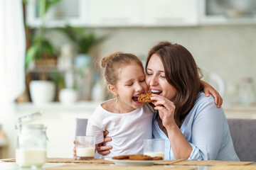 happy loving family, mom and daughter, playing sitting at table and having breakfast at home in...