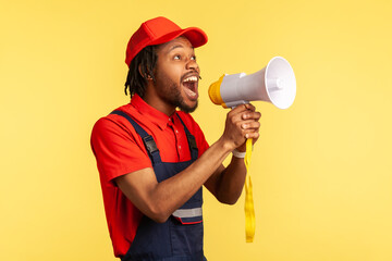 Portrait of bearded handyman wearing blue overalls and red cap screaming announcing about discounts...
