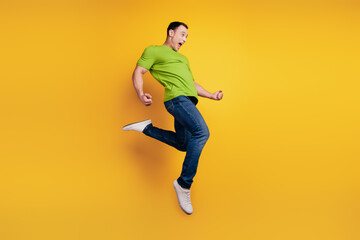 Portrait of crazy winner excited guy jump funny pose on yellow wall