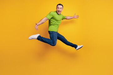 Portrait of crazy energetic guy jump hurry rush enjoy on yellow wall
