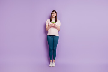 Fototapeta na wymiar Portrait of cheerful charming nice lady hold telephone texting on purple background