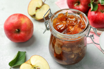 Tasty apple jam in glass jar and fresh fruits on light table