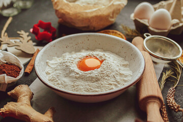 The process of making christmas cookies. Ingredients for baking a pie: flour, confectionery, dishes, kitchen utensils, spruce cookies figurine on a dark background. Christmas gingerbread cookies 2022