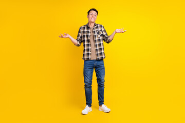 Photo of clueless uncertain guy shrug shoulders wear plaid shirt jeans shoes isolated yellow color background