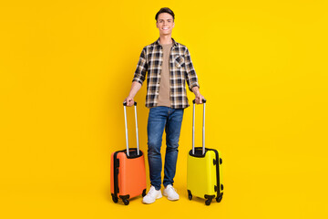 Photo of guy hold two bags beaming smile wear checkered shirt jeans footwear isolated yellow color background