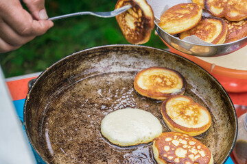The cook prepares pancakes in a frying pan. A man pulls out ready-made pancakes from a frying pan
