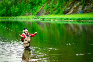 Fototapeta na wymiar The fisherman throws a fishing rod into the river. Fly fishing.