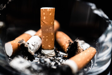 A smoked cigarette in an ashtray on a rough background.