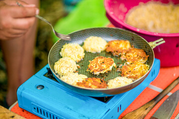 Close-up of meat cutlets in a frying pan on a tile hand holds a fork