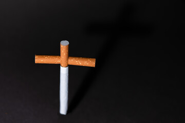 Cross from cigarettes on a black background. Symbol