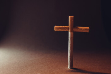 Cigarette in the form of a cross on a dark background