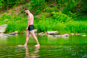 A man walks barefoot on the surface of the water like jesus. The tourist is preparing to sail. The young man enjoys water treatments. The traveler stopped by the river to swim. Copy space