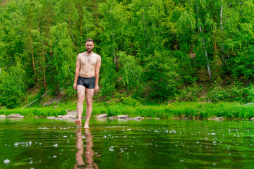 The tourist is cold. The traveler stopped by the river to swim. The young man is fond of water procedures. A man walks barefoot on the surface of the water like jesus. Copy space