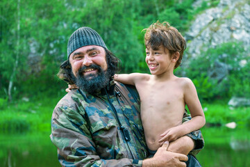 Family photo. A man in camouflage and a boy play with each other and laugh in nature. Portrait of a father and son