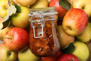 Delicious apple jam in jar on fresh fruits, top view