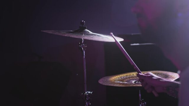 Male Artist hits the drum kit, snare drum and crash. Night show in a musical instrument recording studio. The drummer on the Repetition of rock or metal music band. Musical party. Slow motion