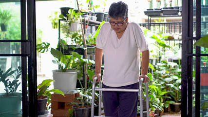 An elderly person or an elderly woman with bone problems is trying to walk using a walker at home.
