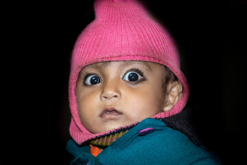 isolated toddler cute facial expression in monkey woolen cape close up shot with black background