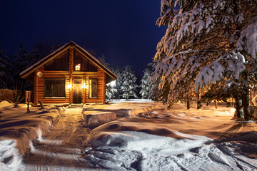 A path in the courtyard leading to a village log house, snow-covered pine trees, a fabulous winter...