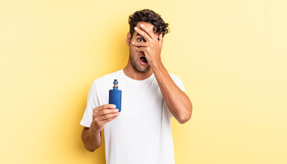 hispanic handsome man looking shocked, scared or terrified, covering face with hand. vaporizer...