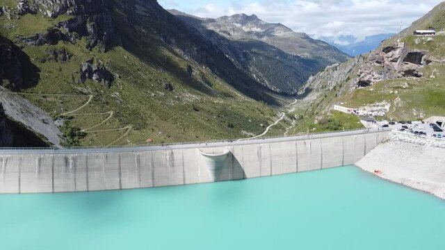 drone flight sideways along the dam wall of the amazing dam wall of the lac de moiry with picture-book landscape of the Swiss Alps in the background, nice sunny weather