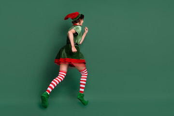 Photo of sweet pretty young lady elf costume headwear running jumping high isolated green color...