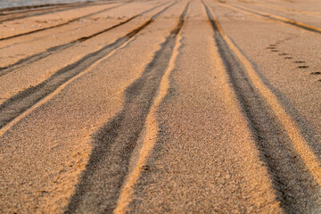 Fototapeta na wymiar Texture of even rows of wheel tracks in the sand.