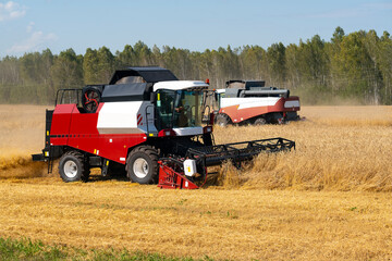 Two harvesters harvest wheat moving towards each other.