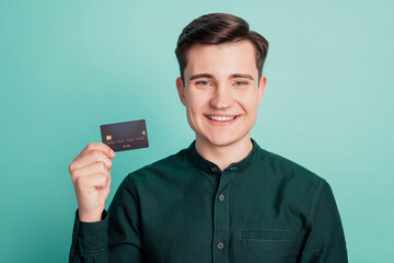 Portrait of charming cool man hold credit card look camera toothy smile on teal background
