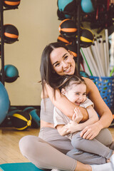 Obraz premium Mom and daughter cuddle. Exercise in the gym with large